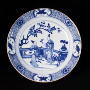 Photo d'une assiette en porcelaine d'époque Kangxi à décor bleu et blanc de personnages sur un balcon.