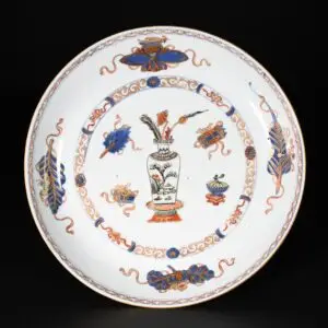 Photo d'une des deux coupes d'une paire de coupes en porcelaine d'époque Kangxi à décor Imari d'un vase fleuri et d'objets précieux.