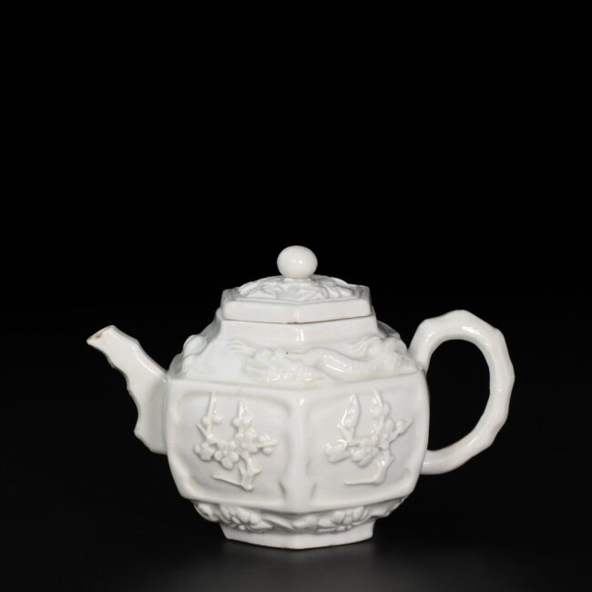 Photo d'une théière en porcelaine "Blanc de Chine", d'époque Kangxi, à décor en relief de dragons et fleurs de prunus.