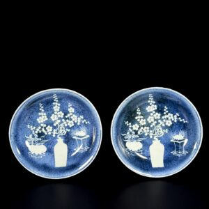 Photo d'une paire de coupes en porcelaine d'époque Wanli à décor d'antiquités en réserve sur un fond bleu poudré.