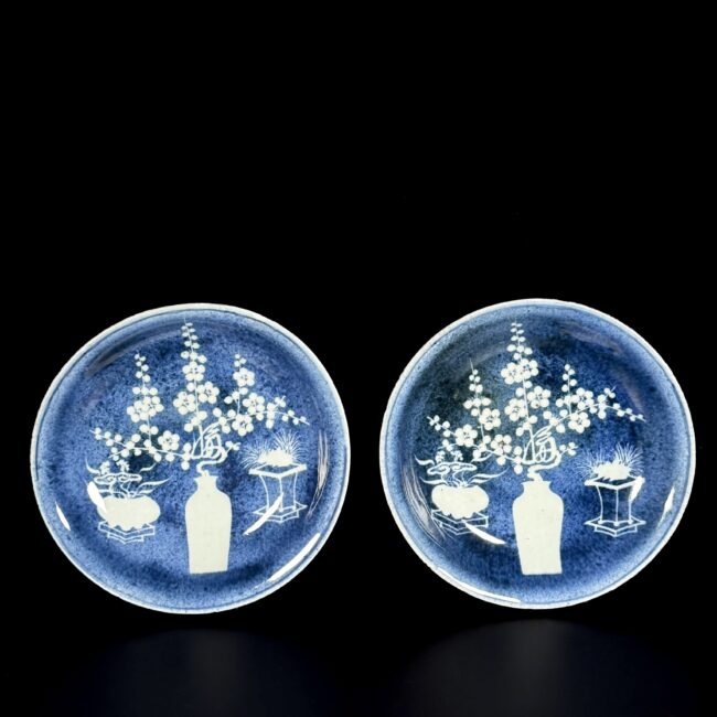 Photo d'une paire de coupes en porcelaine d'époque Wanli à décor d'antiquités en réserve sur un fond bleu poudré.